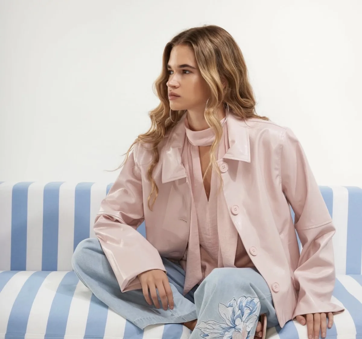 Dames roze lakjas met sjaal en lichtblauwe jeans met bloemenborduur